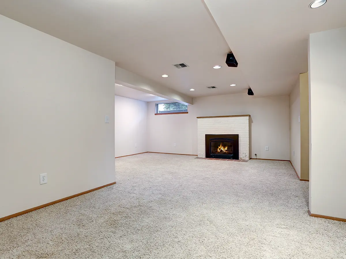 A basement with a fireplace and a carpet floor
