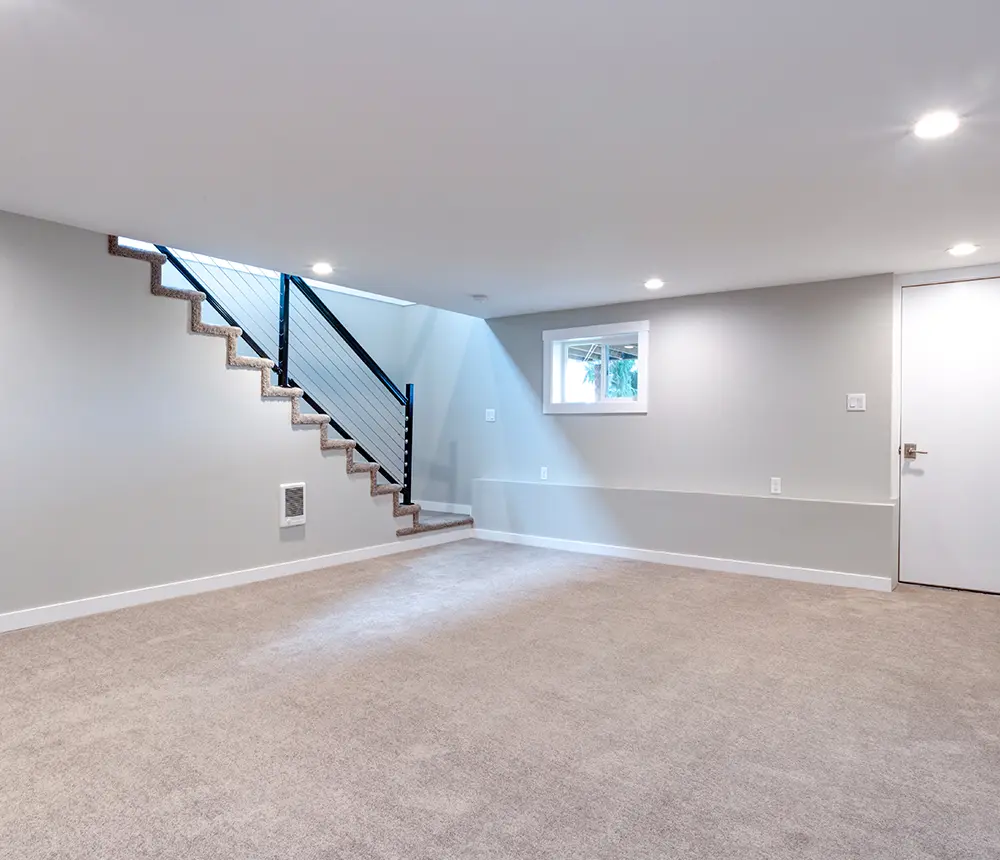 An empty basement with carpet flooring