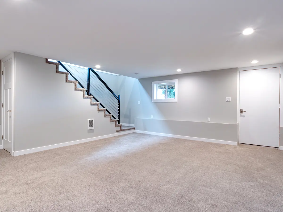 An empty basement with carpet flooring and a white door