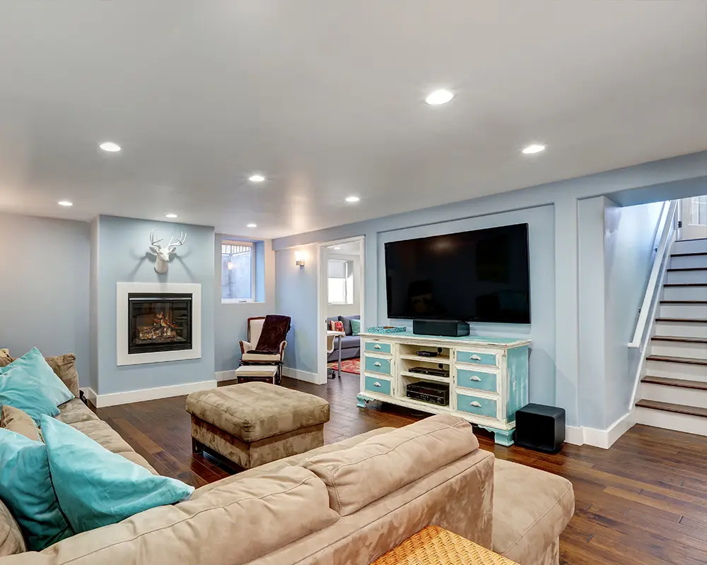 Hardwood flooring in a blueish basement with a beige couch