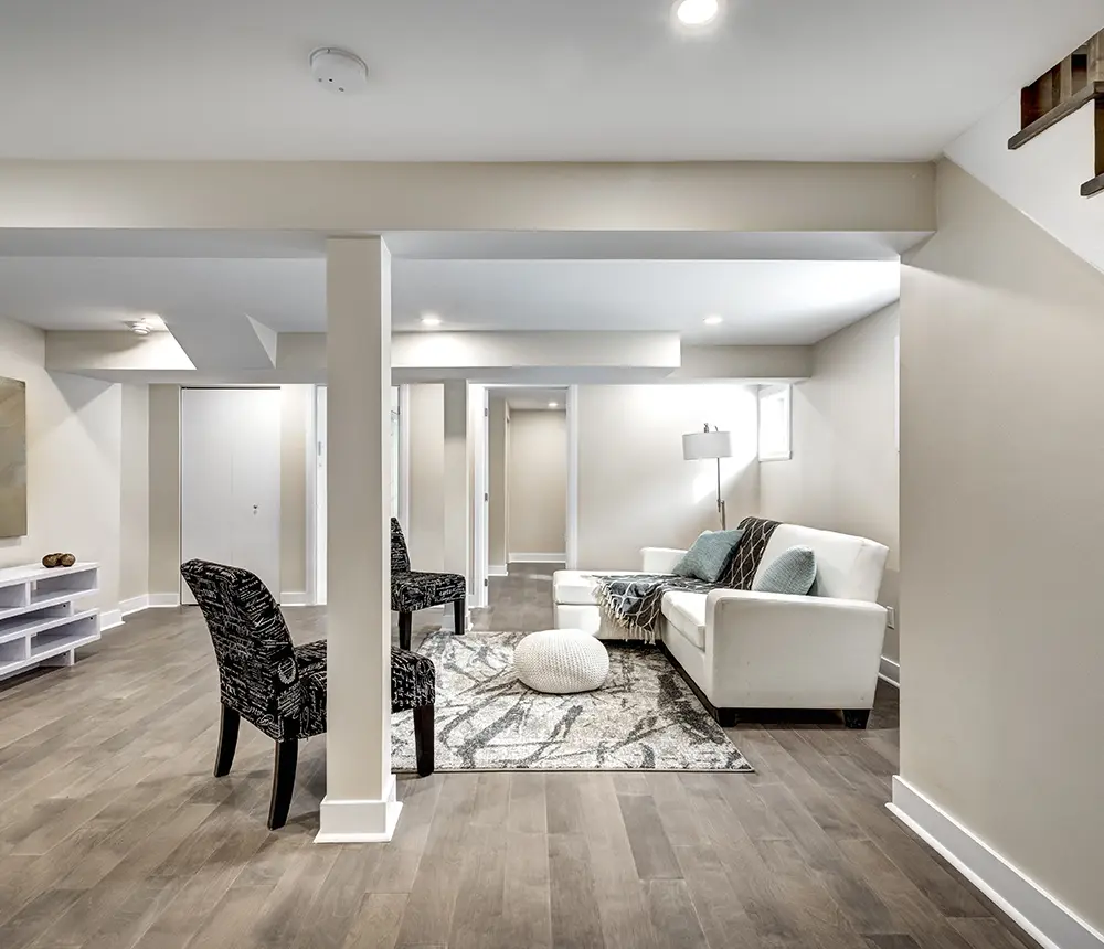 Luxury vinyl flooring in a basement with a white couch and two black chairs