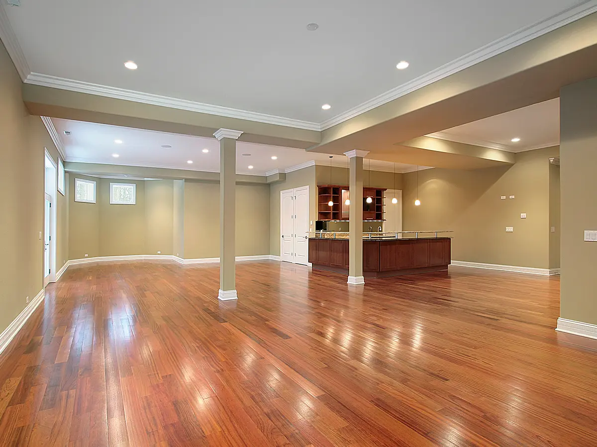 A basement with wood flooring and a kitchenette