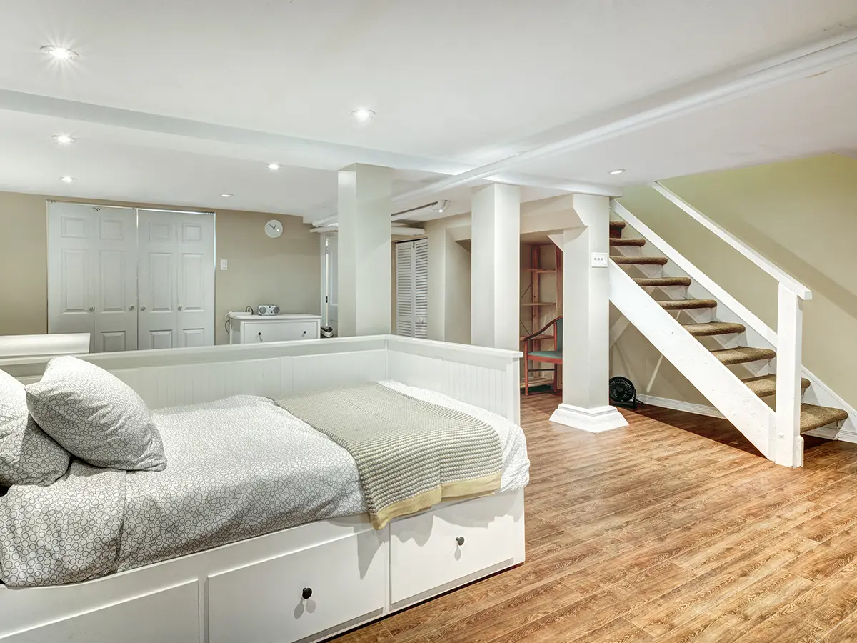 A basement with hardwood flooring and a bed
