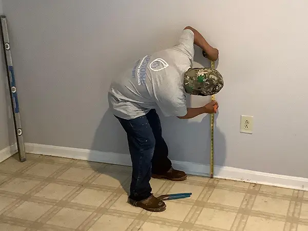 A team of Capstone measuring a wall in a basement