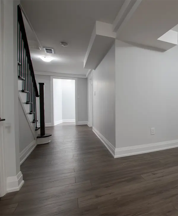 A basement with LVP flooring and a set of stairs with wood railings