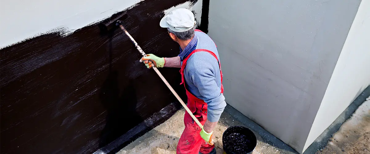 Man Performing Exterior Waterproofing Methods for House Wall