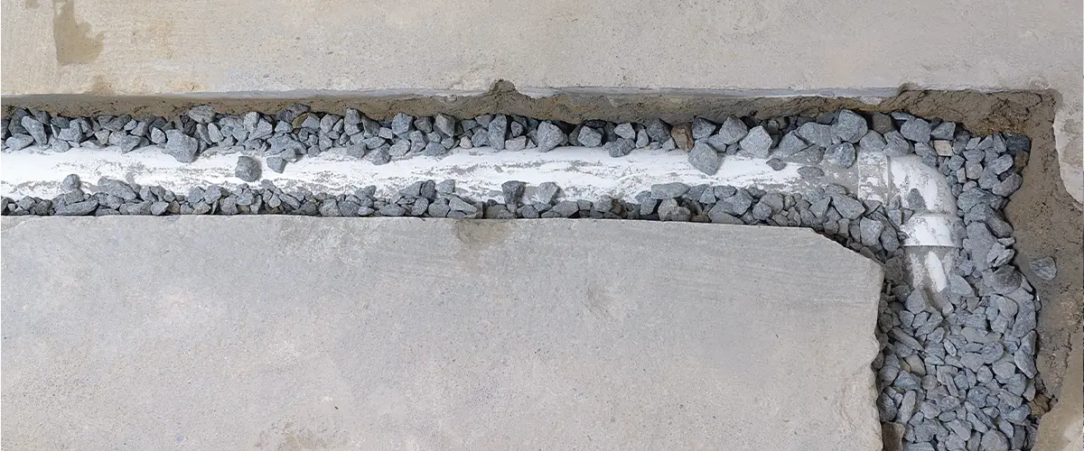 Top view of an unfinished french drain partially covered with drainage rocks